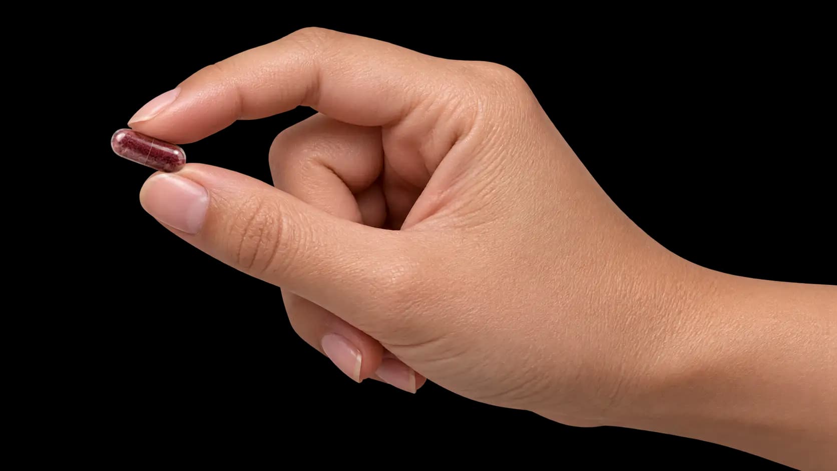 One Beet Boost capsule held between finger and thumb